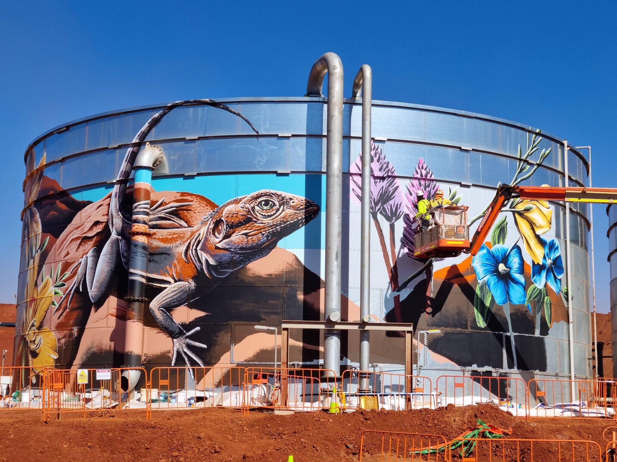 Brenton See painting a monumental wildlife mural on water tanks near Tom Price